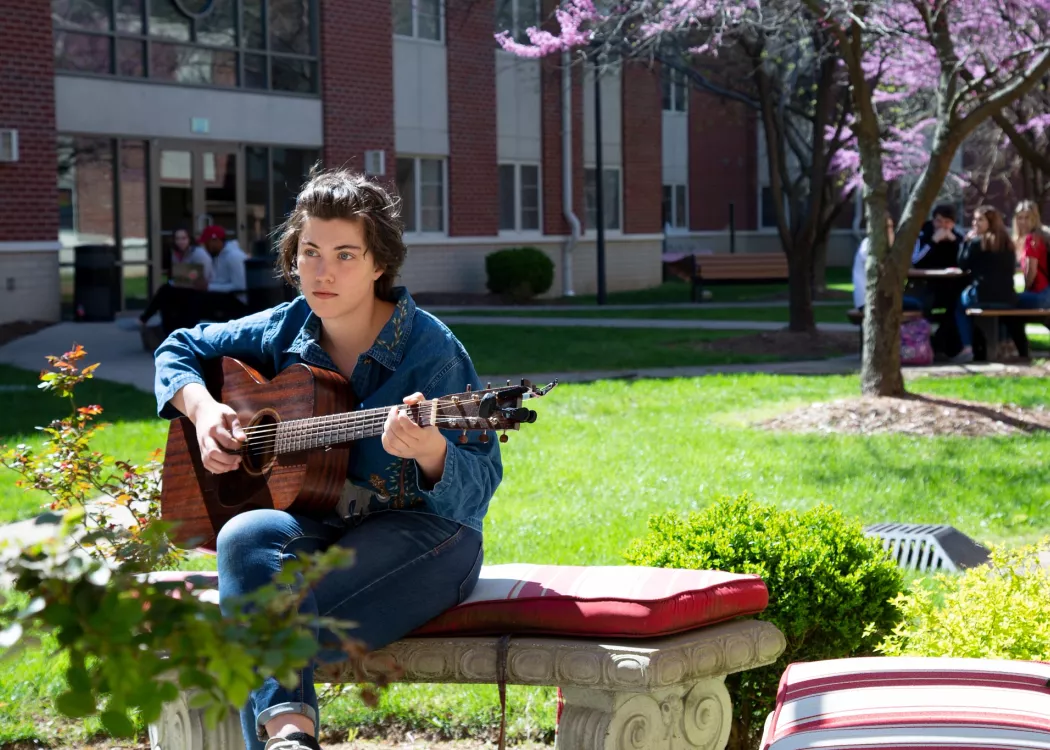 Student plays guitar on a spring day