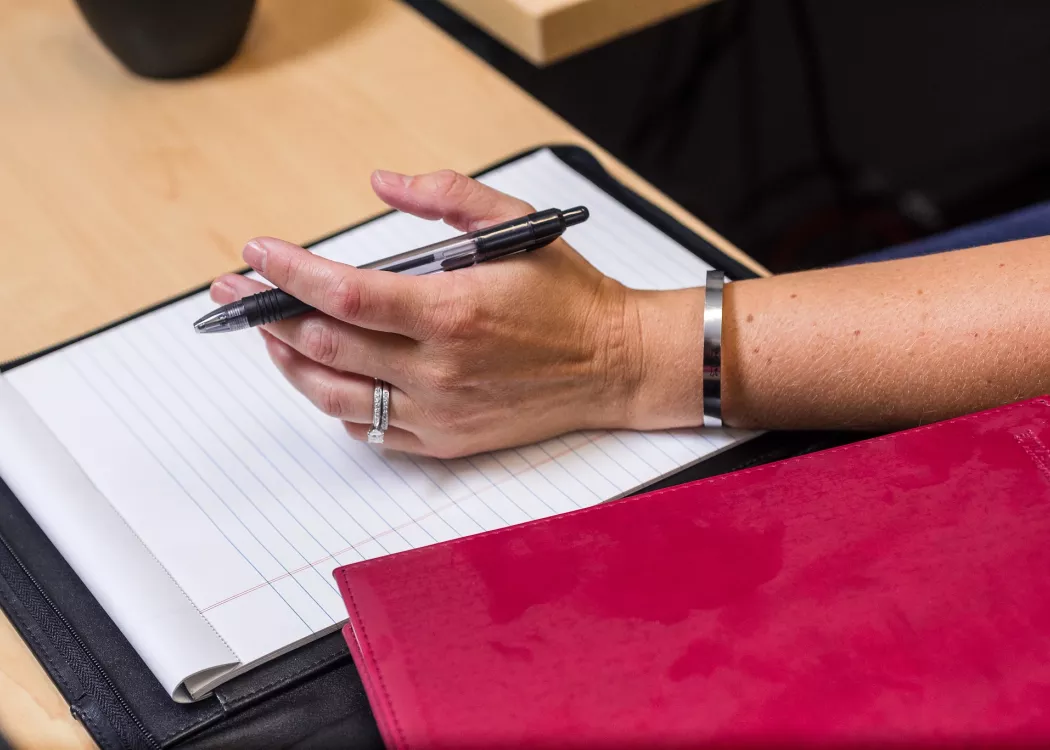 Close-up of female hand prepared to take notes on legal pad