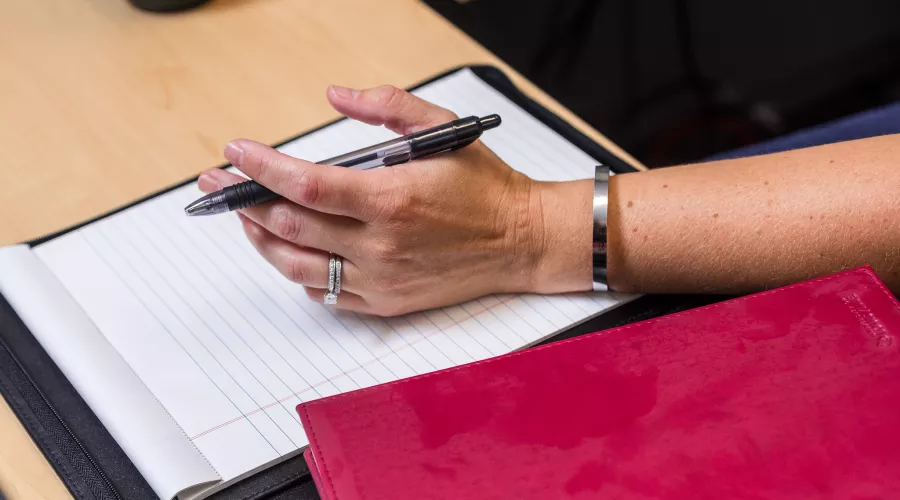 Close-up of female hand prepared to take notes on legal pad