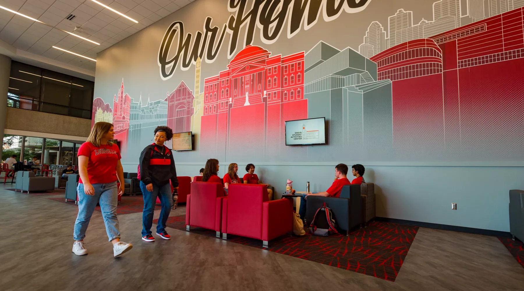 Two students in the foreground walking past other students in the SAC lounge