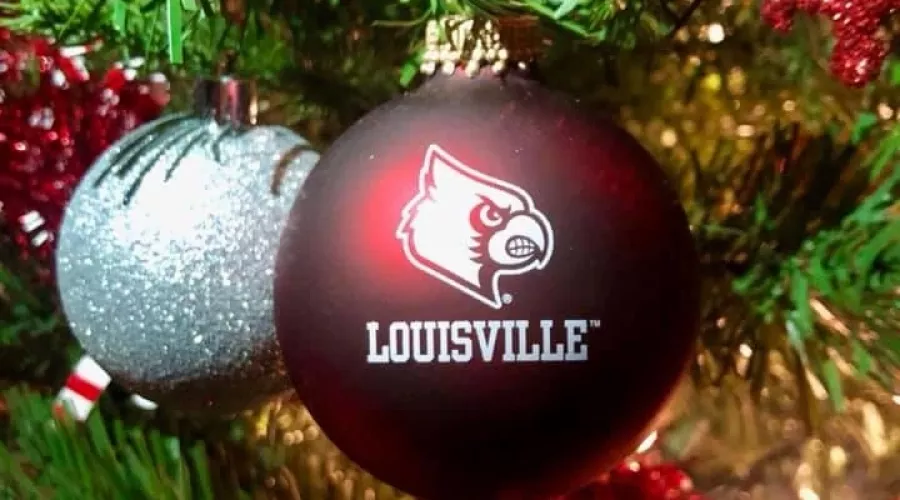 A UofL themed holiday tree with focus on a red ornament with Louisville and Louie logo.