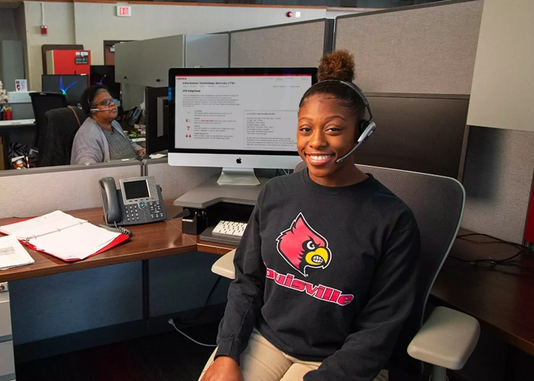 Student worker sitting at desk with headset on for phone calls.
