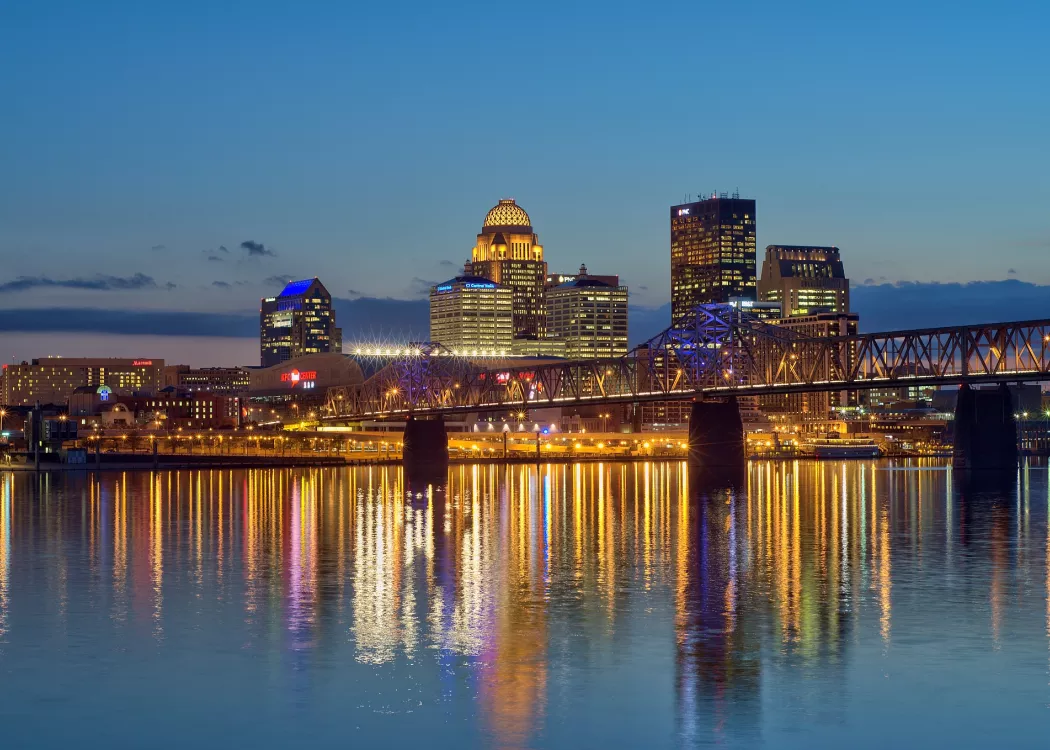 Dusk skyline photo of the Louisville waterfront with light reflections in the Ohio River