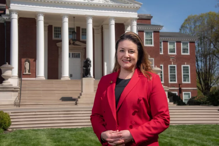 Woman in red stands in front of Grawemeyer Hall.