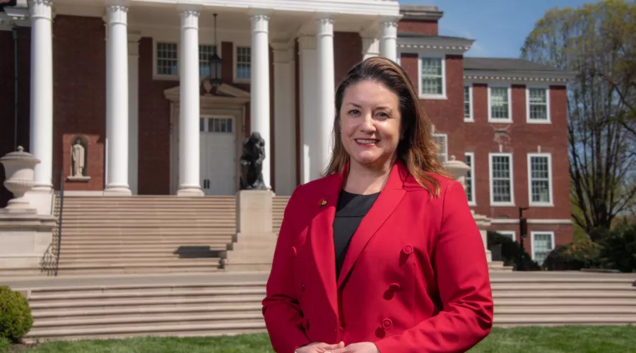 Woman in red stands in front of Grawemeyer Hall.