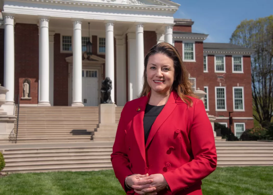 Woman in red stands in front of Grawemeyer Hall.